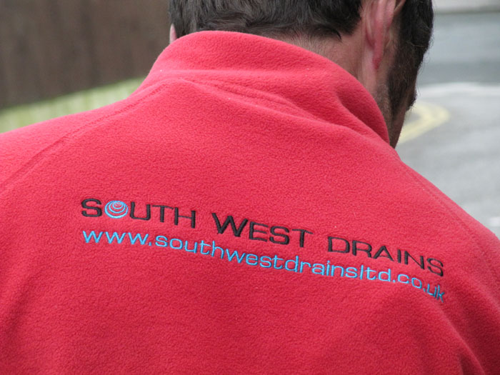 The back of a red South West Drains work fleece
