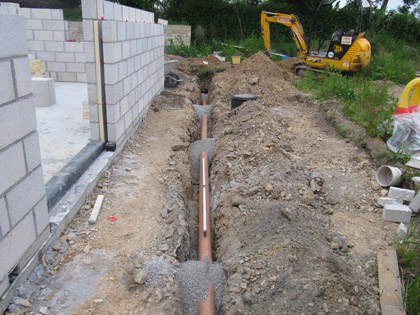 A new pipe laid in a trench beside a block wall