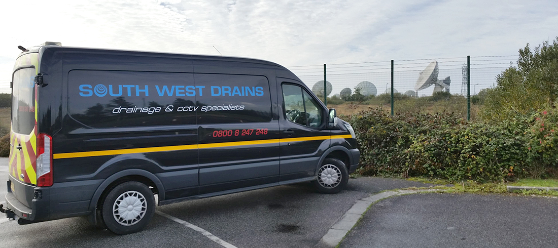 The navy South West Drains van parked beside fencing